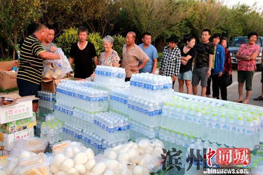 8月24日，志愿者在潍坊寿光市营里镇为灾民免费发放物资。　梁犇　摄