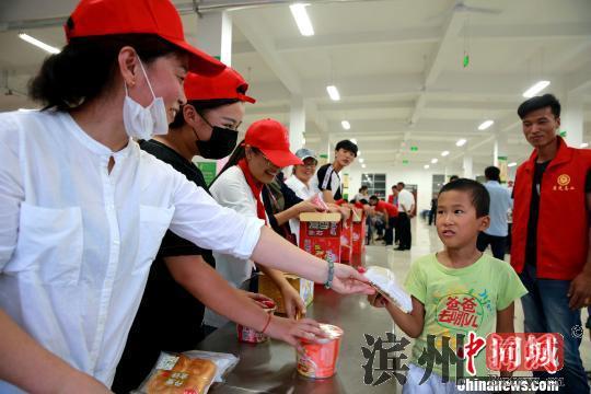 8月24日，志愿者在潍坊寿光市营里镇第二初级中学安置点为灾民发放救援物资。　梁犇 摄